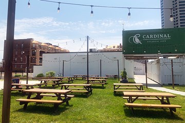 Daytime picture of Cardinal Restaurant's Garden area with picnic tables and strung lighting.