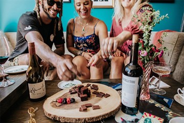 People enjoying a chocolate flight with wine and cocktails in a stylish atmosphere.