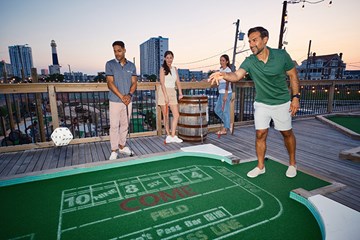 Man rolling large dice with group playing round of min-golfer.