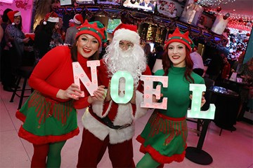 Resorts Candy Cane Lounge with Holiday elves posing with Santa holding letters spelling out NOEL.