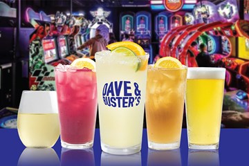 Dave & Buster's various cocktails and ice cold drinks with Arcade games in background.