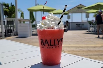 Bally's Frozen Cocktail with whipped cream, cherry and straw in a Bally's cup. Sun shining at Bally's Beach Bar in Atlantic City