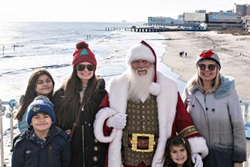 Santa Claus poses for photo at the Steel Pier The Wheel deck overlooking the beach and boardwalk in Atlantic City.