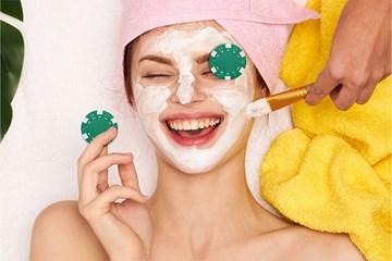 Woman getting facial at a spa with poker chip covering her eye and smiling.