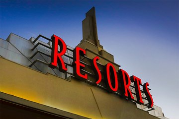 Resorts sign lit up in red against a darkening blue sky.