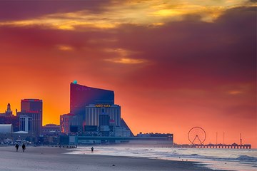 Sunrise from the beach with casino resorts, and piers visible along the Boardwalk in Atlantic City.