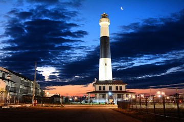 Absecon Lighthouse in evening with crescent moon above blue hour sky. Photo by Matt Crowne.
